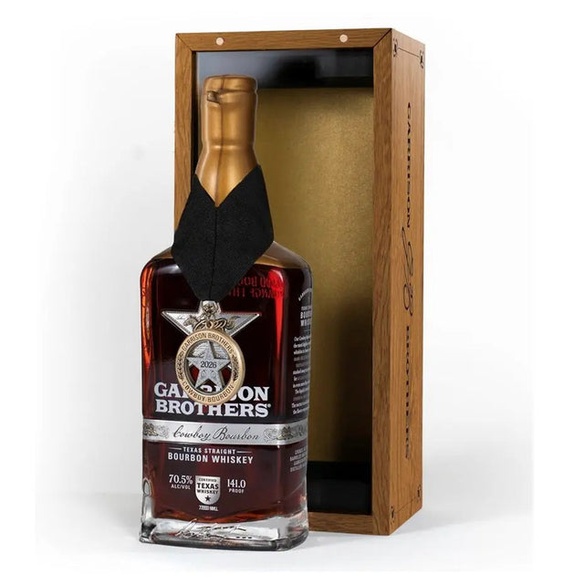 Bottle of Garrison Brothers 2026 Cowboy Bourbon Texas Straight Bourbon Whiskey with a neck medallion beside its open wooden presentation box