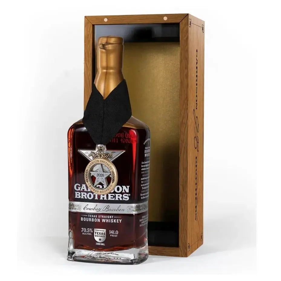 Bottle of Garrison Brothers 2026 Cowboy Bourbon Texas Straight Bourbon Whiskey with a neck medallion beside its open wooden presentation box