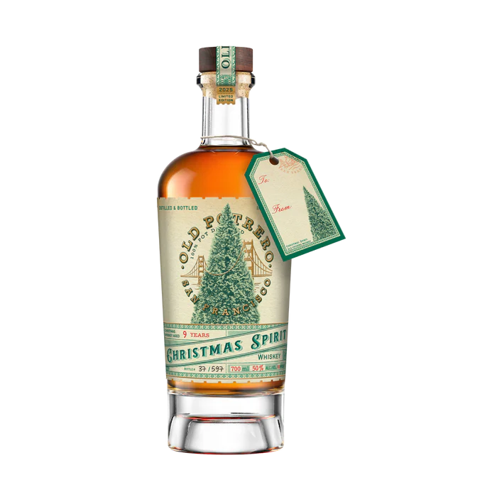 A 700mL bottle of Old Potrero 2025 Christmas Spirit Whiskey 9 Year Limited Edition, featuring a festive label with a decorated Christmas tree and a green and gold gift tag attached to the neck.