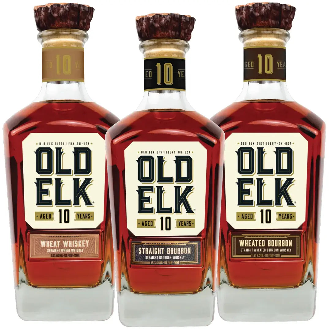 Three bottles from the Old Elk 10 Year Series Bundle—Bourbon Whiskey, Wheated Bourbon Whiskey, and Wheat Whiskey by Old Elk Bourbon—are arranged side by side against a white background, each showcasing rich amber liquid and wooden-topped corks.
