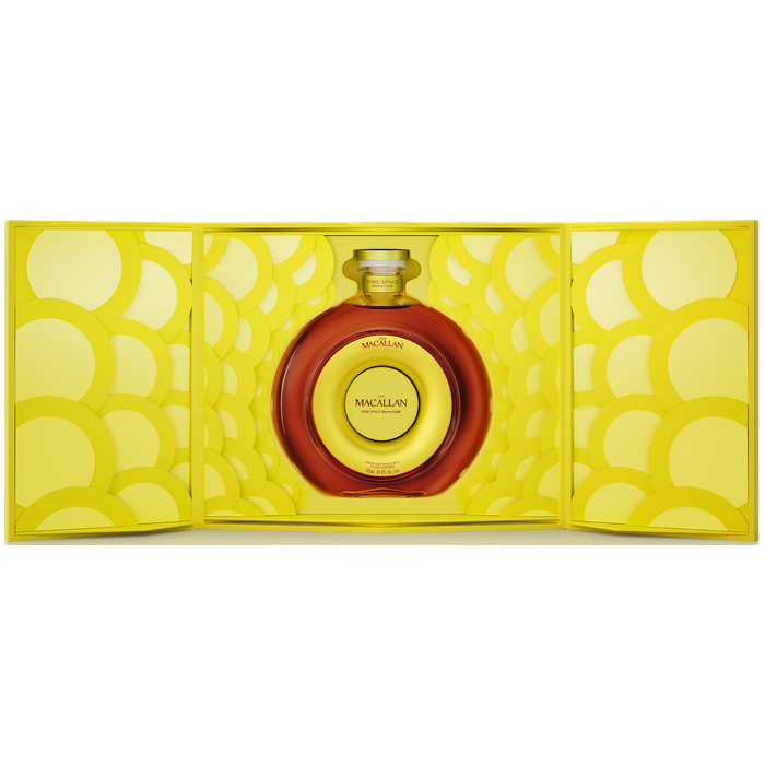 A round bottle of The Macallan TIME : SPACE Sherry Cask Single Malt Scotch Whisky sits centered in an open, bright yellow box with a circular pattern, nestled within the decorative interior.