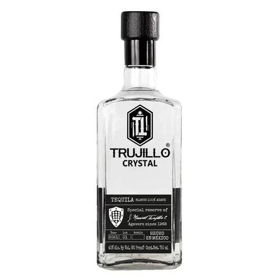 Trujillo Tequila Crystal Tequila Blanco comes in a clear glass bottle with a black cap. Its black and white label features the Trujillo Tequila logo and product info in English and Spanish, celebrating 100% agave Mexican tequila craftsmanship.