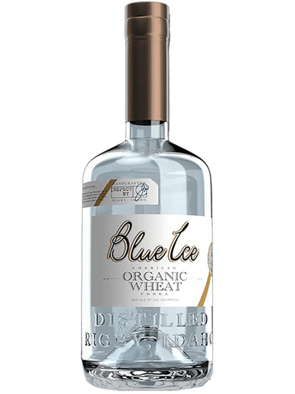 A clear glass bottle of Blue Ice Organic Wheat Vodka, featuring a silver and white label, copper-colored cap, and “Distilled Organic” embossed on the lower part.