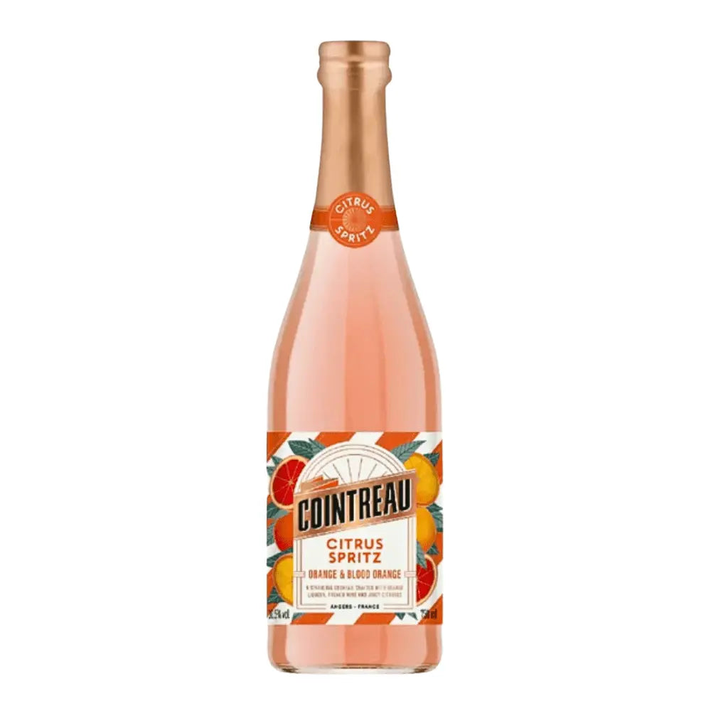 A bottle of Cointreau Citrus Spritz Orange & Blood Orange features a pink-orange liquid, orange and gold label with citrus fruit illustrations, a copper cap, and bears the Cointreau brand name.