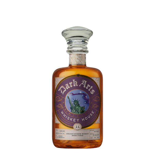 A bottle of America 250 Years of Spirit 5X Blend Bourbon from Dark Arts Whiskey House, featuring a purple ornate label with the Statue of Liberty and crescent moon, and topped with a clear glass stopper.