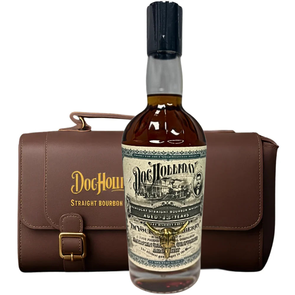 A bottle of Doc Holliday 13 Year Doctor's Bag Single Barrel Bourbon with a vintage-style label stands before a brown leather carrying case embossed with "Doc Holliday Straight Bourbon Whiskey" in gold.