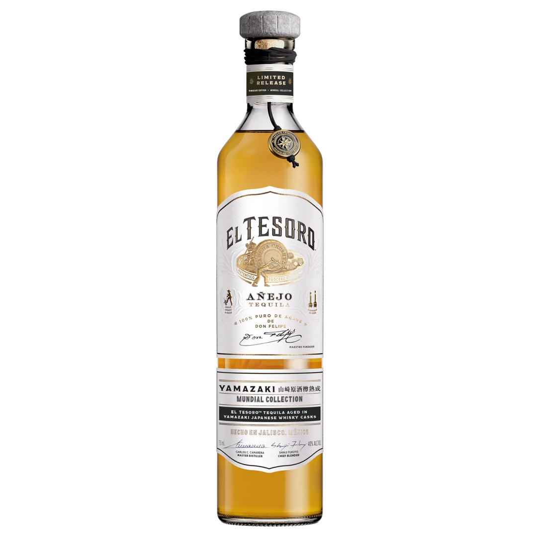 A tall, clear bottle of El Tesoro Tequila’s Mundial Limited Edition Anejo Yamazaki Finished features a gold and white label, a secondary label noting Yamazaki cask aging near the base, a silver cap, and golden tequila inside.