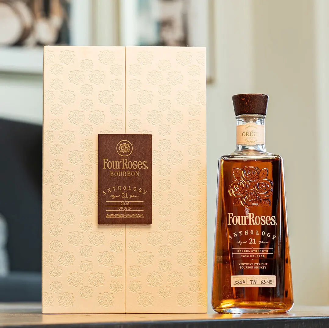 A bottle of Four Roses The Anthology Series Chapter 1: Origin 21 Year Bourbon from Main Street Liquor stands beside its embossed cream box with a brown label on a reflective surface, capturing elegance and rich Kentucky bourbon heritage.