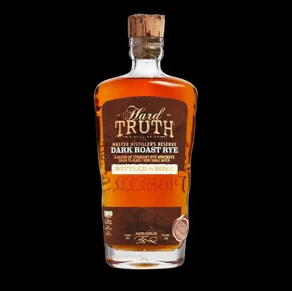 A bottle of Hard Truth Master Distiller’s Reserve Dark Roast Rye Bottled in Bond by Hard Truth, a limited whiskey release, featuring a cork top, dark brown label, and gold accents, set against a black background.