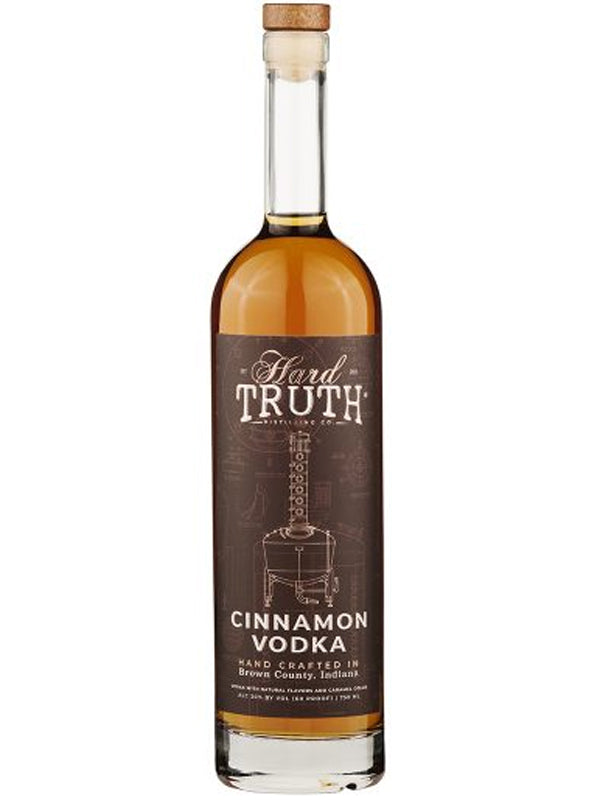 A tall, clear glass bottle of Hard Truth Cinnamon Vodka features a cork top and dark brown label with white text, showcasing this premium hand-crafted vodka from Hard Truth in Brown County, Indiana.
