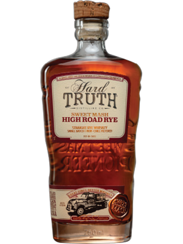 A bottle of Hard Truth Sweet Mash High Road Rye Whiskey by Hard Truth, featuring a cork top and a cream-and-red label with gold accents, a vintage truck illustration, and a bronze medallion at the bottom.