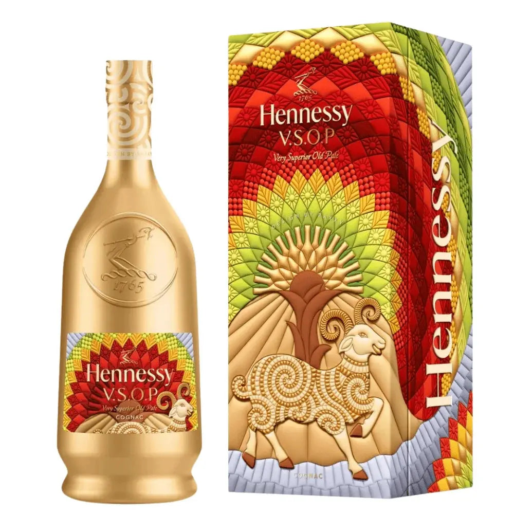 The Hennessy V.S.O.P Year Of The Goat Limited Edition by Raxxy features a striking gold bottle and a vibrant box adorned with mosaic-inspired patterns in red, yellow, and green, along with a stylized ram—a unique collaboration between Hennessy and Raxxy.