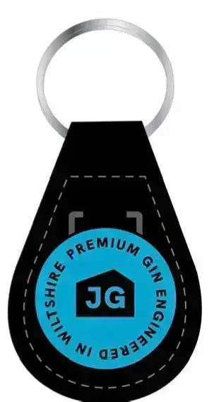 The James Gin The Tupac 2 Bottle Set W/ Souvenir Gift Key Chain by James Gin US includes a black leather keychain with brown stitching and a blue emblem reading 'PREMIUM JAMES GIN ENGINEERED IN WILTSHIRE' with 'JG' in a house icon, reflecting British craft gin quality.