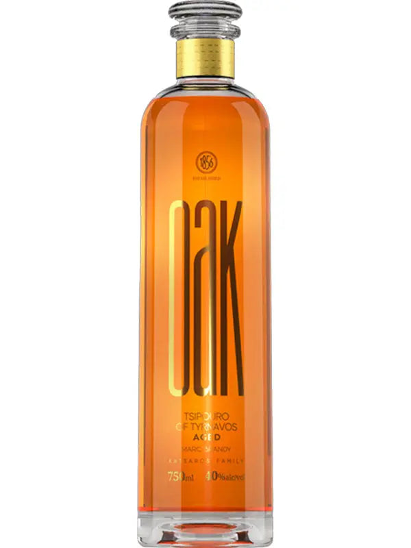 A tall, clear glass bottle of Katsaros Oak Aged Tsipouro by Katsaros features a silver cap and label with "OAK" in bold letters. The Greek spirit inside has an amber-golden hue, reflecting its oak aging.