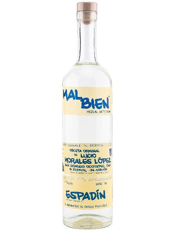 A tall, clear glass bottle of Mal Bien White Tape Espadin Morales mezcal with a wooden cork and cream-colored labels featuring blue and black text that highlight “Espadín” and artisanal mezcal details from brand Mal Bien.