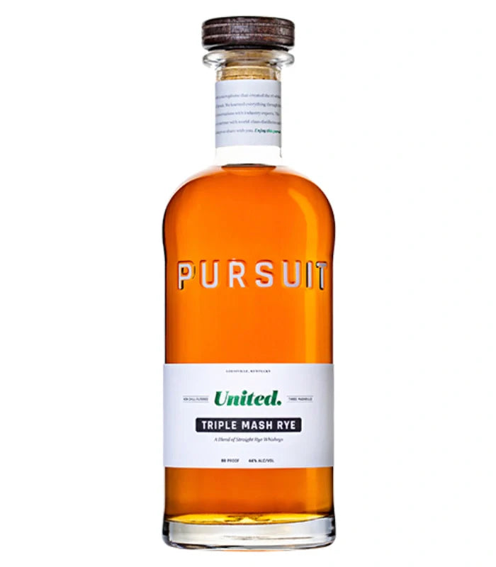 A 700mL bottle of Pursuit United Triple Mash Rye Whiskey by Pursuit Spirits, with amber liquid, a wooden cap, and a white label with green and black text. "PURSUIT" is embossed on the upper half of the bottle.