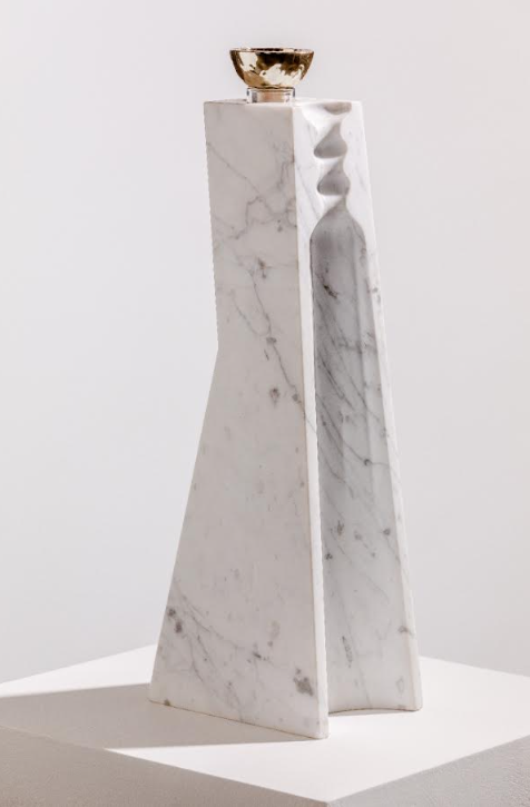 A tall, modern white marble sculpture with angular sides and a gold bowl honors the refined elegance of Volcan De Mi Tierra Coleccion I Hacienda La Gavilana Anejo Tequila, standing proudly on a white pedestal.