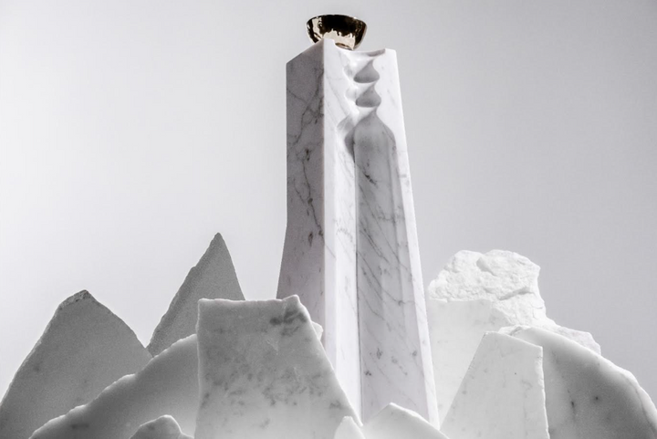 A tall, white marble sculpture with graceful curves and a metallic cup reflects the elegance of Volcan De Mi Tierra Coleccion I Hacienda La Gavilana Anejo Tequila, its refined form highlighted against a light backdrop.