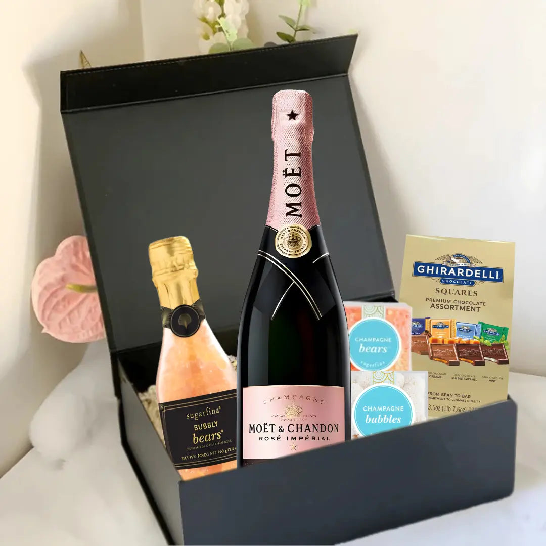 The Premium Champagne Gift Box by Main Street Liquor features a bottle of Moët & Chandon Rosé, a mini sparkling wine, Ghirardelli chocolate squares, and champagne-flavored gummies in a luxurious black box on a white surface.