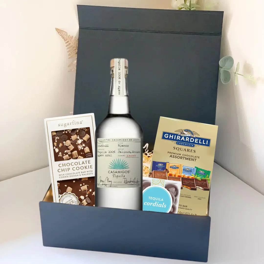 The Premium Tequila Gift Box by Main Street Liquor features Casamigos tequila, a Sugarfina chocolate chip cookie bar, and Ghirardelli gourmet chocolate squares, all upright in an elegant display.