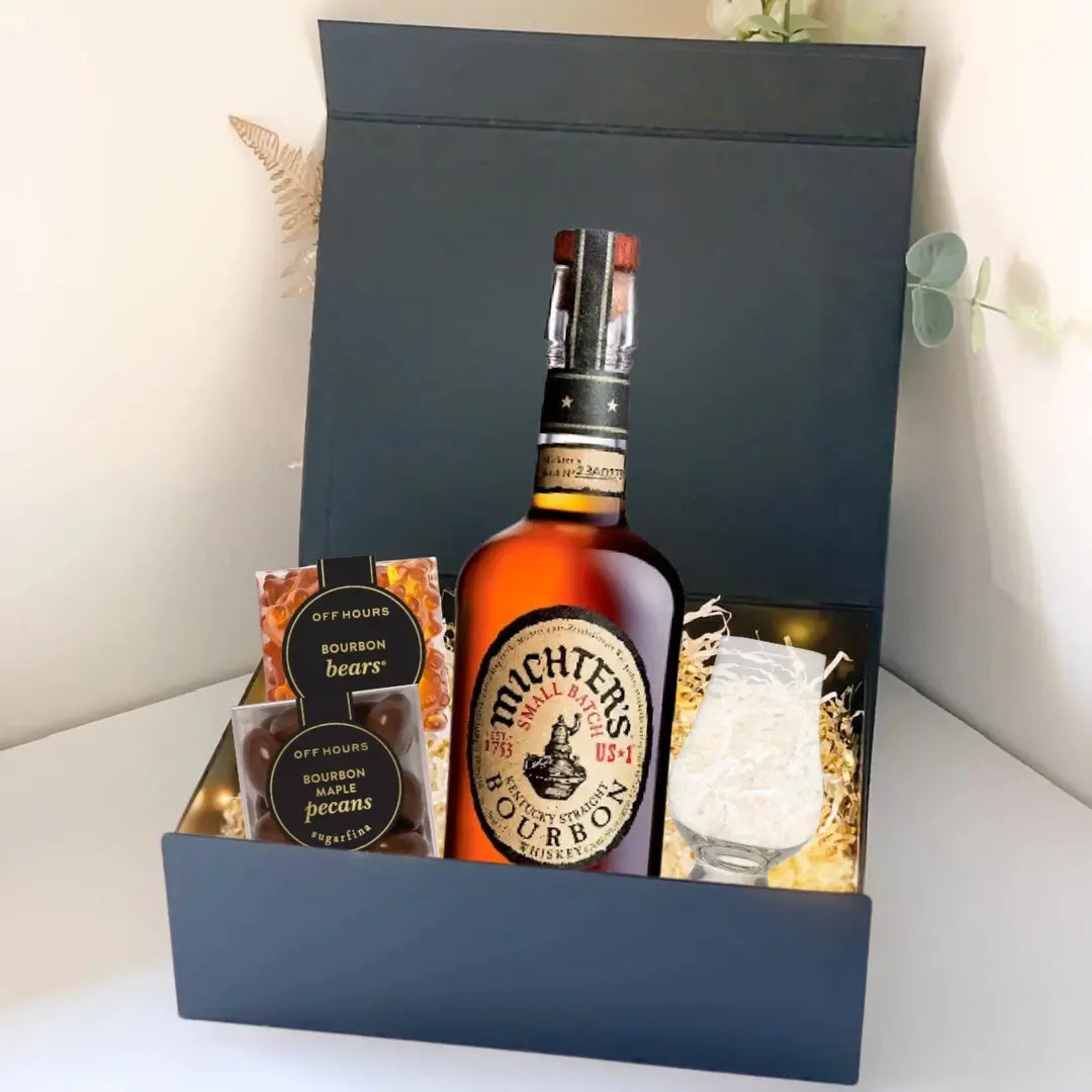 The Premium Bourbon Gift Box by Main Street Liquor includes Michter’s bourbon, a glass with ice, honeycomb snack, bourbon bears, and bourbon pecans—elegantly arranged with decorative straw for the perfect whiskey gift.