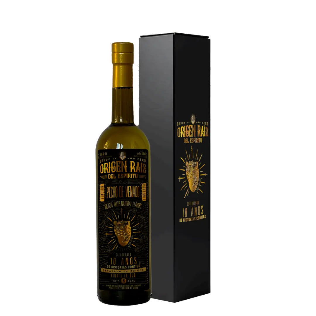 A dark glass bottle of Origen Raiz Pecho de Venado Anniversary Edition Mezcal (PRE-ORDER) stands beside a matching black and gold box, featuring gold lettering, a deer head design, and the label "10 años de producción continua.
