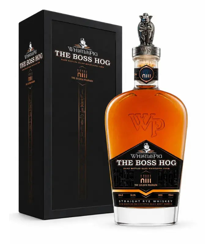 A bottle of WhistlePig The Boss Hog XIII The Golden Pharaoh Straight Rye Whiskey (Pre-Order) from WhistlePig stands in front of its black, gold-accented box. This limited edition whiskey showcases a decorative silver cap and amber liquid inside.