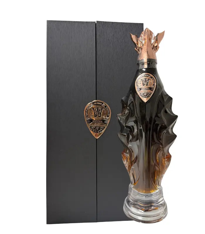 The World Whisky Society Masterfully Crafted 15 Year Ex-Buffalo Trace Kentucky Bourbon 130.6 Proof comes in a unique dark glass bottle with bronze accents, a dragon-themed cap, and a crest, paired with a tall black box featuring a bronze emblem.