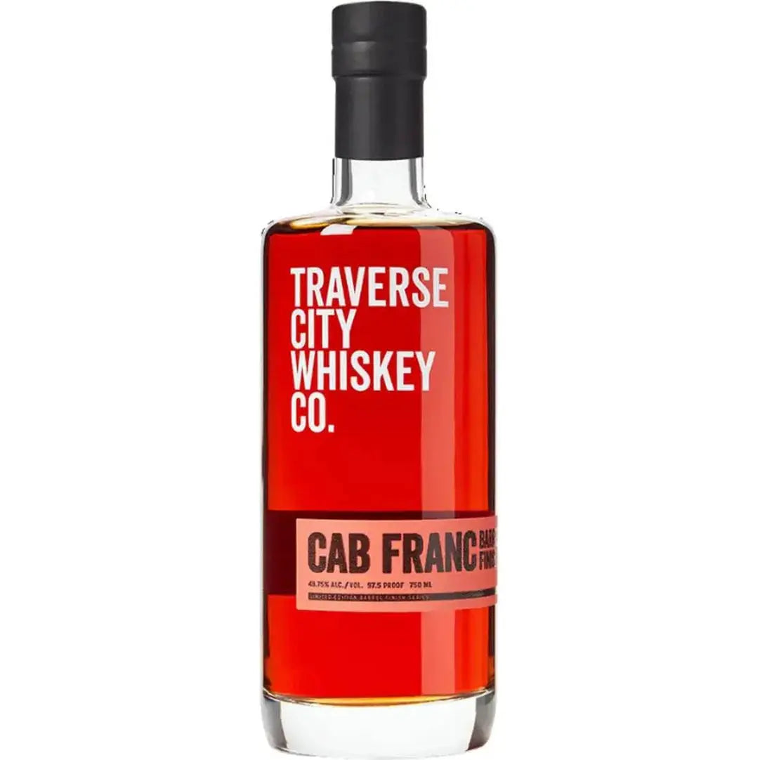 A bottle of Traverse City Whiskey Co. Cab Franc Barrel Finish features a black cap, bold red and white label on clear glass, and displays its rich amber whiskey.
