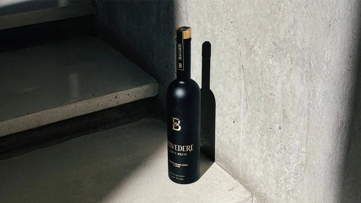 A bottle of Belvedere Vodka’s Dirty Brew Organic Coffee Flavored Vodka rests elegantly on a concrete surface.