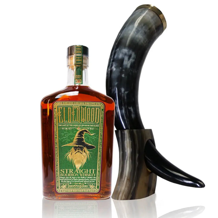 A bottle of Eldenwood Straight Bourbon Whiskey with a green and gold label featuring Eryndor the Elder’s wizard hat, placed beside a polished curved drinking horn on a matching stand.
