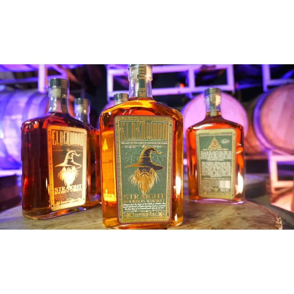 Three bottles of Eldenwood Straight Bourbon Whiskey are displayed on a barrel, with barrels and purple lighting behind them. The label shows Eryndor the Elder, a raven in a wizard hat, highlighting this enchanting whiskey from Eldenwood.