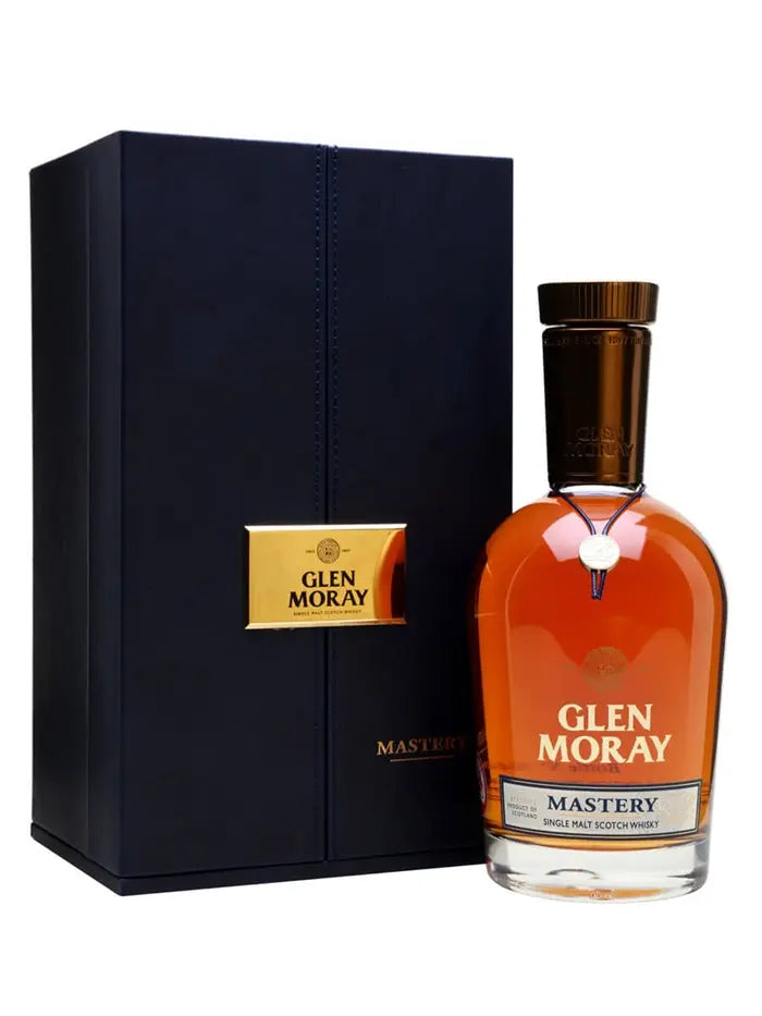 A bottle of Glen Moray Mastery 120th Anniversary Single Malt Scotch Whisky is displayed next to its elegant, dark blue and gold gift box.