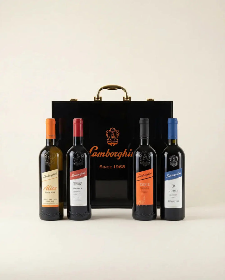 The Lamborghini Ultimate Wine Gift Set—Trescone, Era, Taurus, and Alice—is displayed before a black luxury gift case with gold handles featuring the Lamborghini Wine &amp; Spirits Collections logo and "Since 1968".