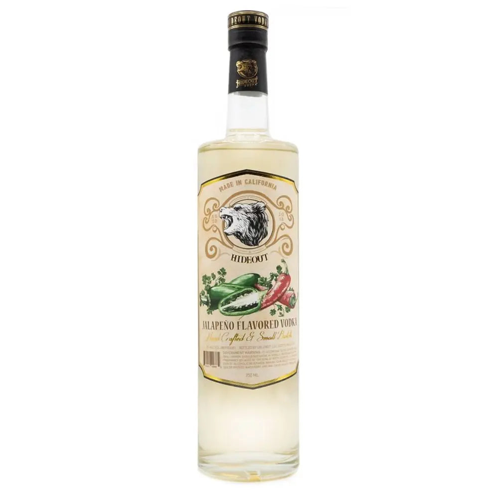 A bottle of Hideout Spicy Jalapeno Flavored Vodka from Hideout Vodka, featuring a clear bottle with a beige and gold label adorned with an eagle’s head and images of red and green jalapeños. The vodka inside appears slightly tinted.