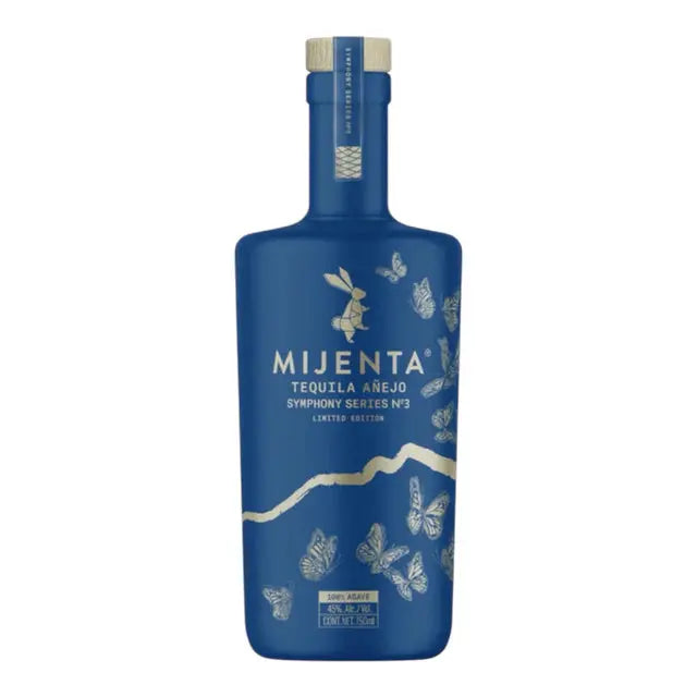 A limited edition blue bottle of Mijenta Tequila Añejo Symphony Series No. 3 from Jalisco, featuring gold butterflies and text on the label, plus a matching blue cap with gold accents.