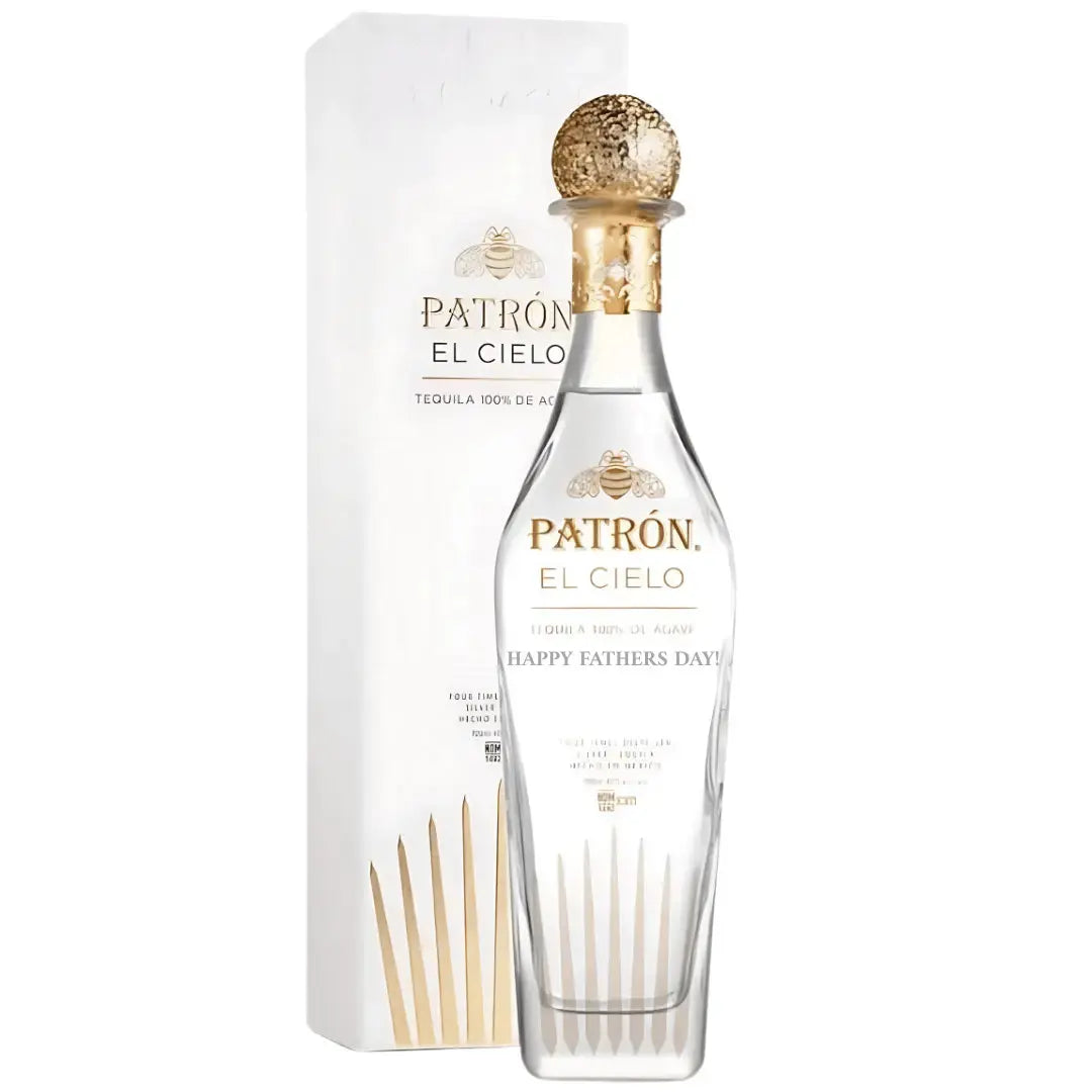 A clear 700mL bottle of Patron El Cielo tequila, engraved with "HAPPY FATHERS DAY!", sits beside a white and gold gift box, featuring a stylish gold and clear stopper.