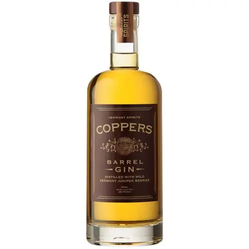 A bottle of Vermont Spirits Coppers Barrel Aged Gin displays a brown label with gold accents and a wooden cap. This small batch Vermont gin shows an amber hue, reflecting its expert barrel aging.