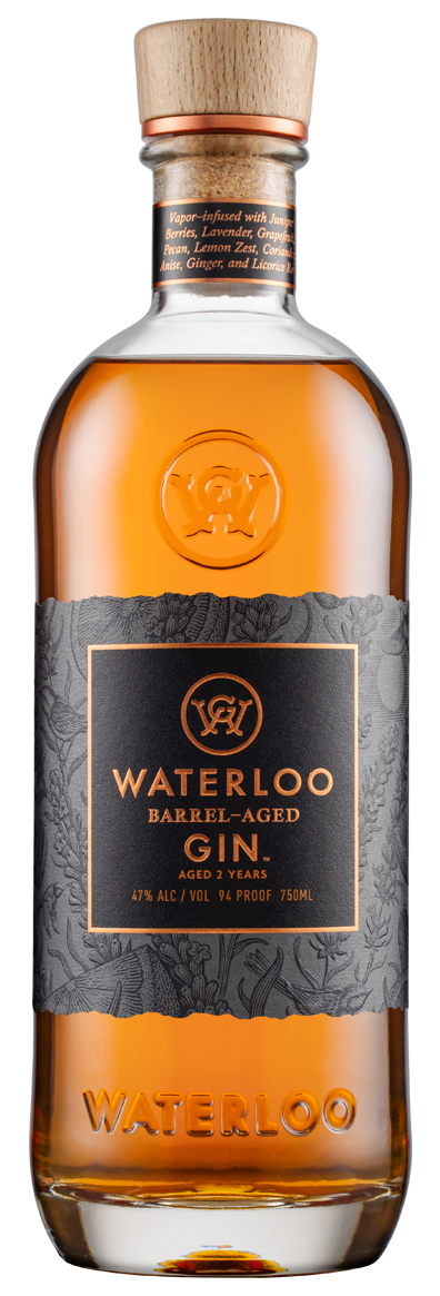 A 750ml glass bottle of Waterloo Gin’s Barrel-Aged Gin features a wooden cap, amber liquid, gray label with 47% ABV, 94 proof, and notes its Texas Hill Country botanicals and 2-year aging.