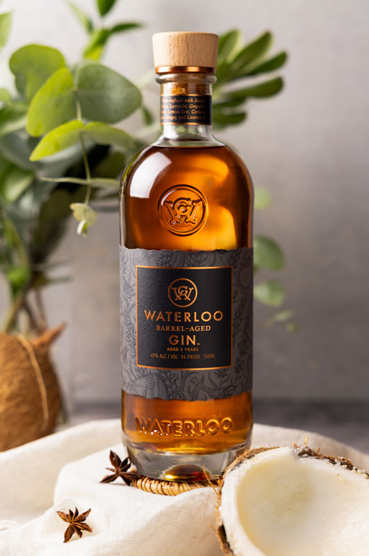 A bottle of Waterloo Barrel-Aged Gin by Waterloo Gin rests on a table, capturing the spirit of the Texas Hill Country.